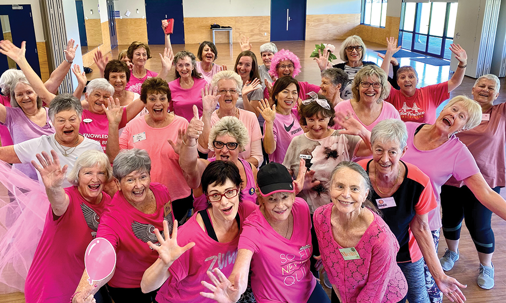 Group of ladies posing around a camera in pink 